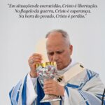 Imagem do Vatican News mostrando o papa Leão XIV com vestes litúrgicas brancas e azuis decoradas com cruzes, de olhos fechados em profunda oração enquanto eleva uma hóstia branca sobre um cálice ornamentado em prata e ouro. Logo acima dele, sob o logotipo vermelho e preto do canal, destaca-se a citação em itálico: